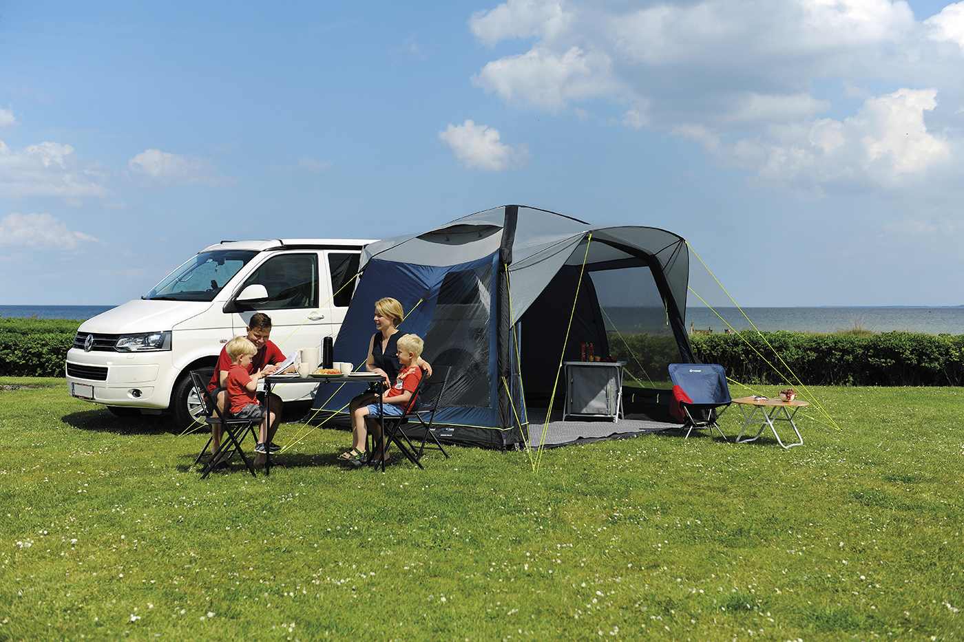 Motorhome awnings and people sat in field